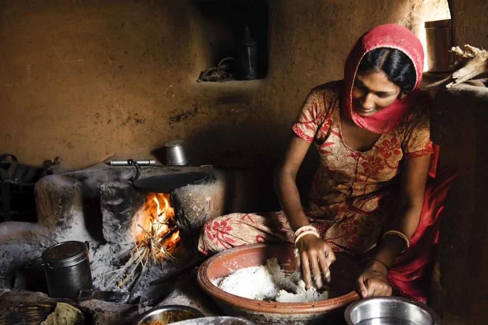femme préparant des chapatis traditionnellement cuits au feu de bois en Inde